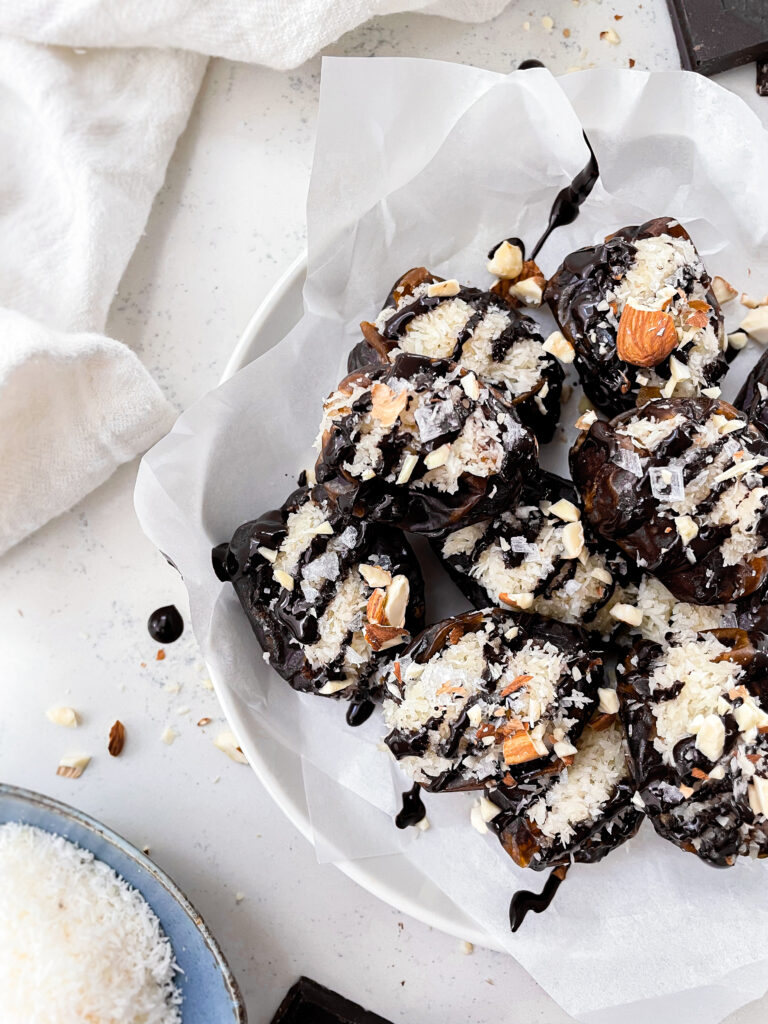 dates stuffed with coconut on a plate next to a bowl of coconut