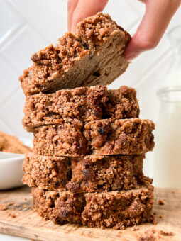 coffee cake slices stacked on a cutting board next to a bottle of milk