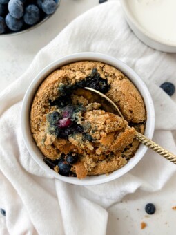 baked oats in a ramekin next to a glass of milk and bowl of berries