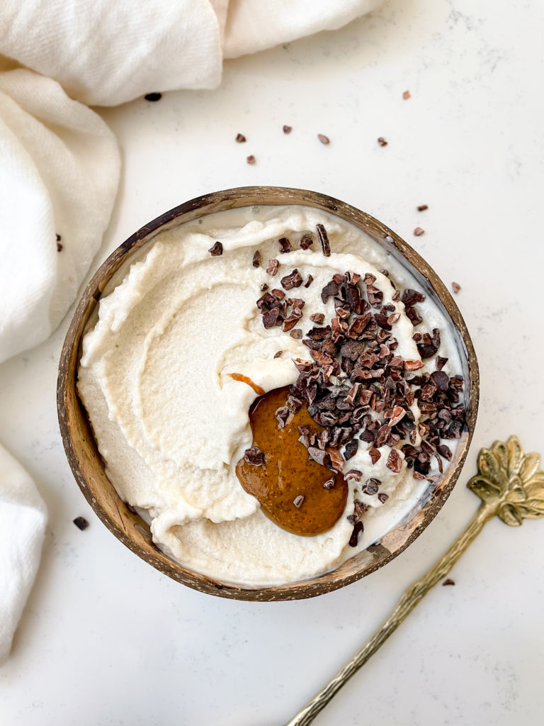 nice cream in a coconut bowl topped with granola and nut butter