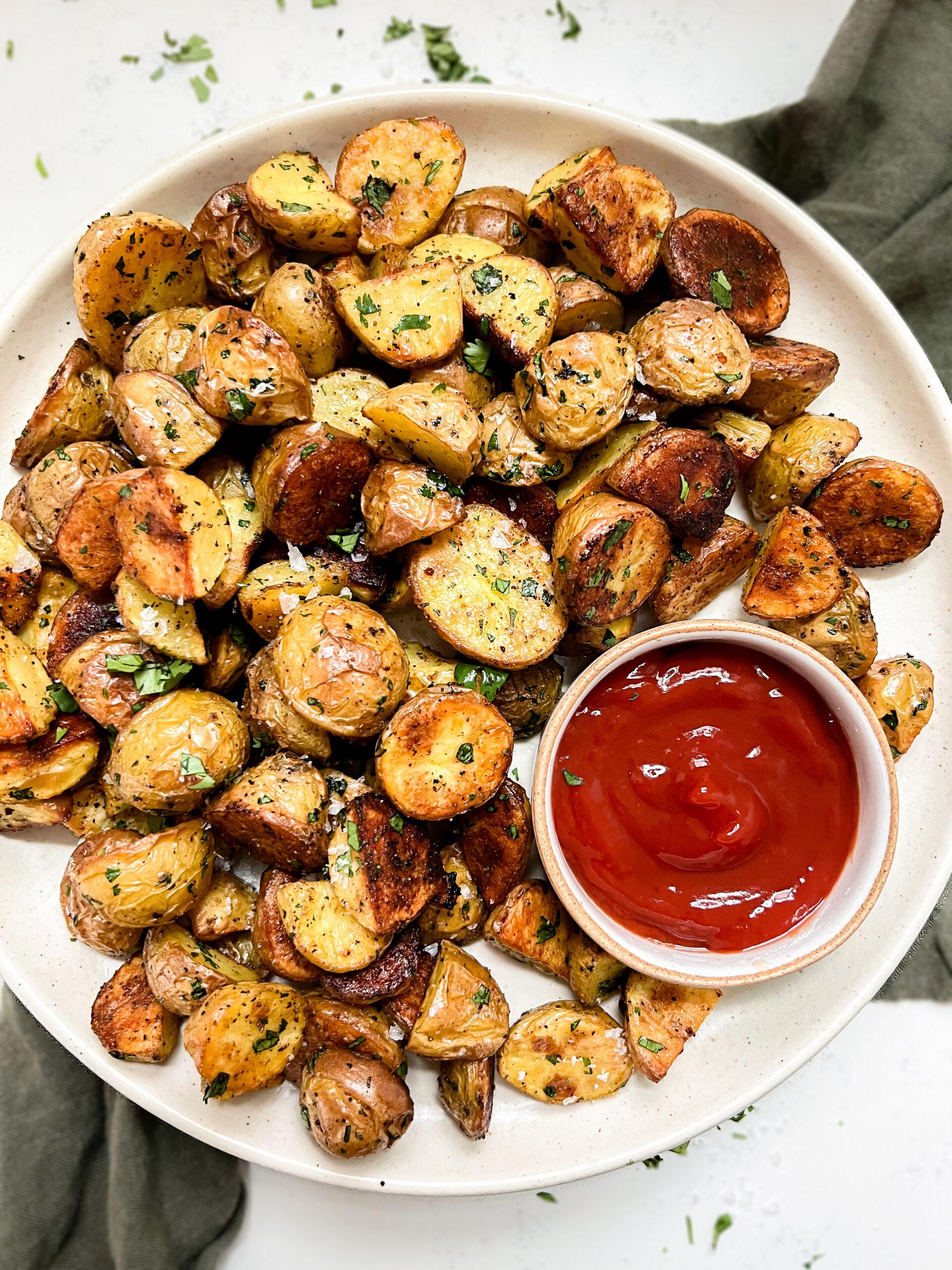crispy oven baked potatoes on a beige plate next to a bowl of ketchup