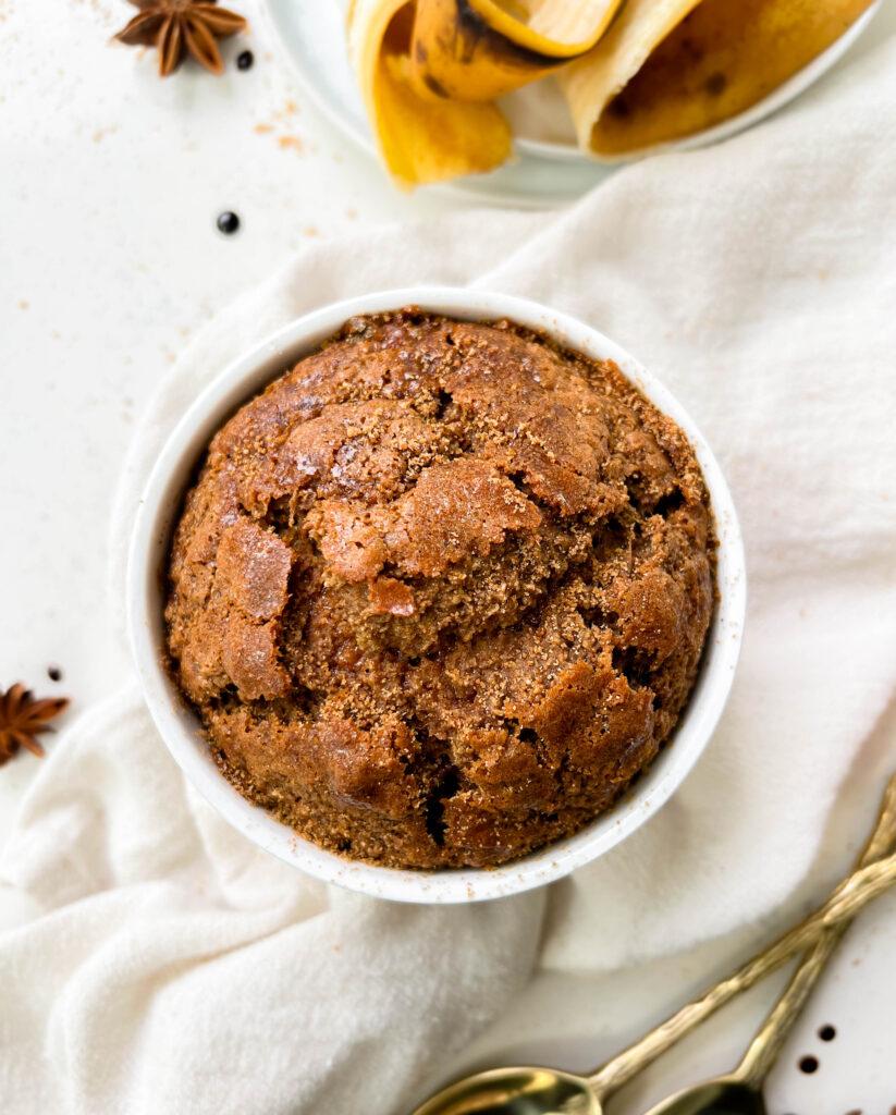 fluffy gingerbread baked oats in a ramekin next to banana peels and coconut sugar