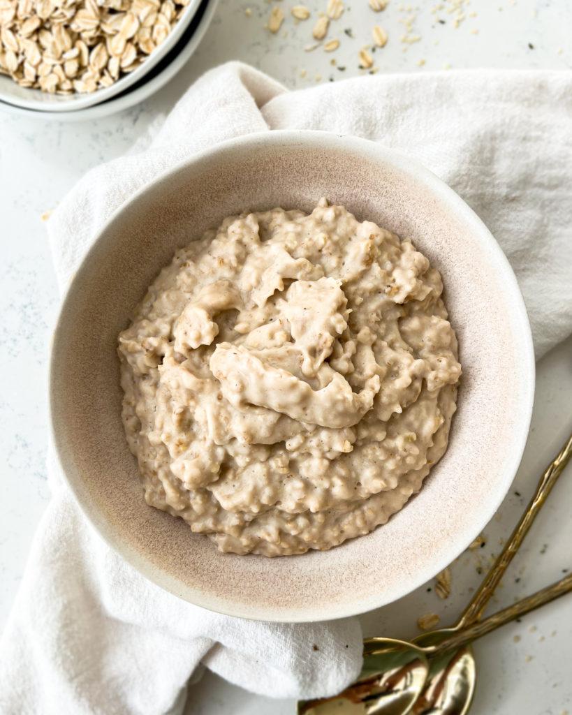 oatmeal in a white bowl next to a bowl of rolled oats