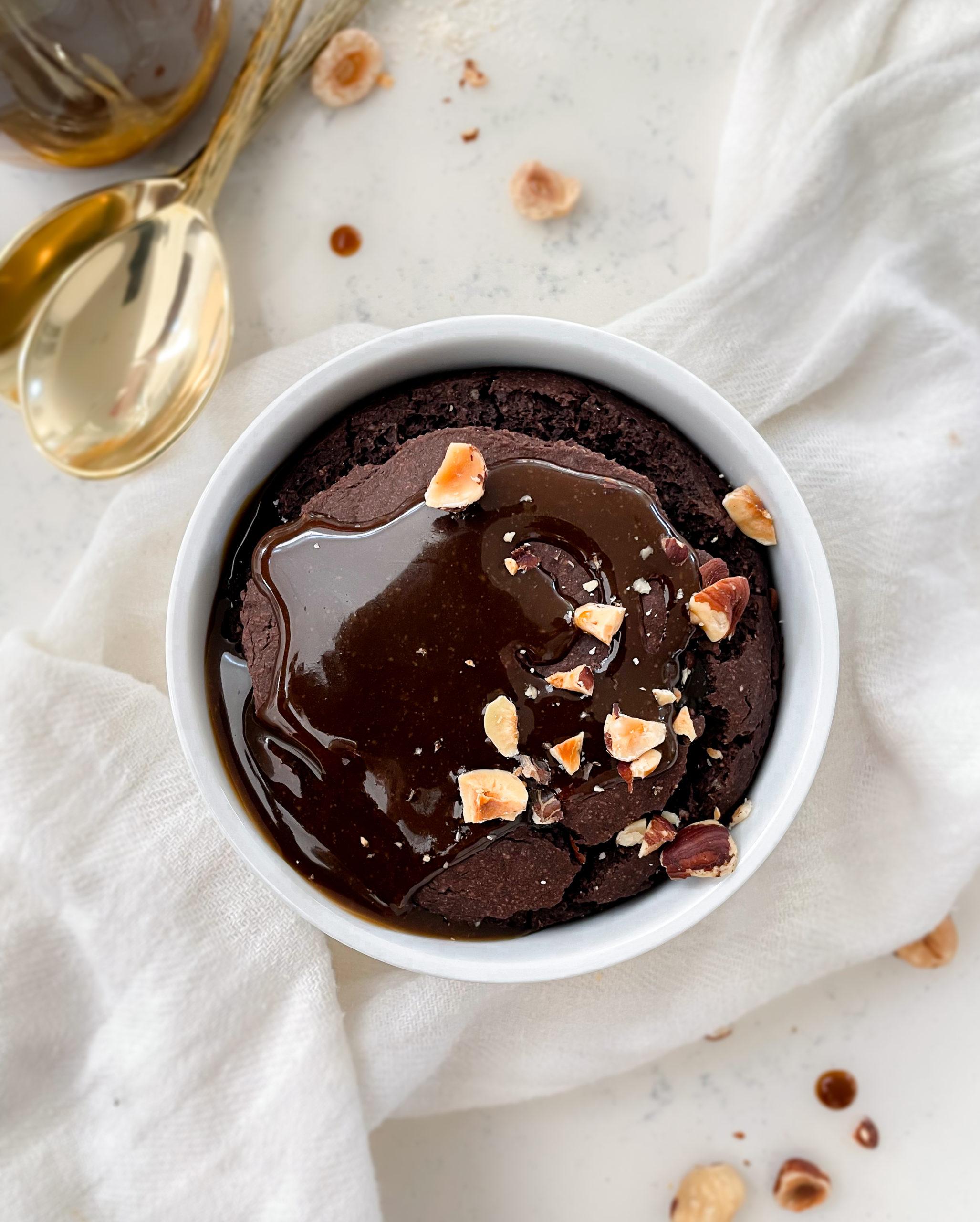 chocolate oats in a ramekin on top of a cloth napkin next to golds spoons and a jar