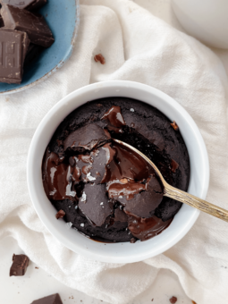 brownie in a mug next to a bowl of chocolate
