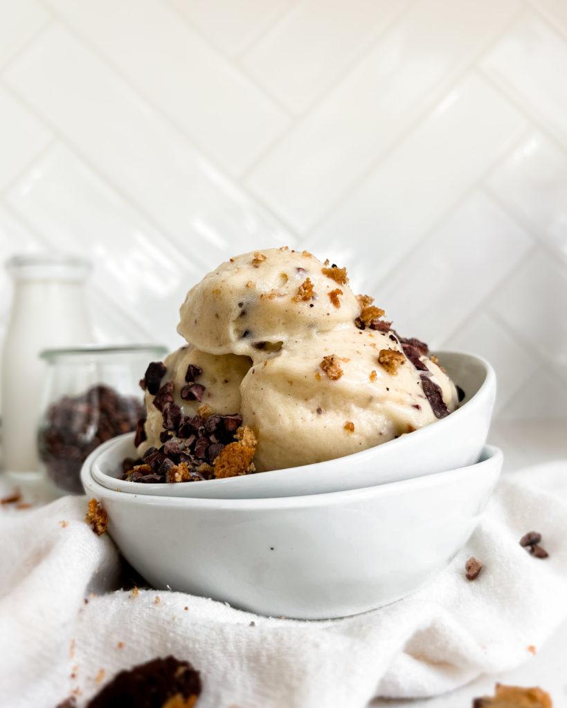 smoothie in a white bowl next to a jar of milk and cacao nibs