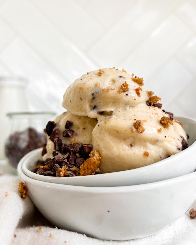 smoothie in a white bowl next to a jar of milk and cacao nibs