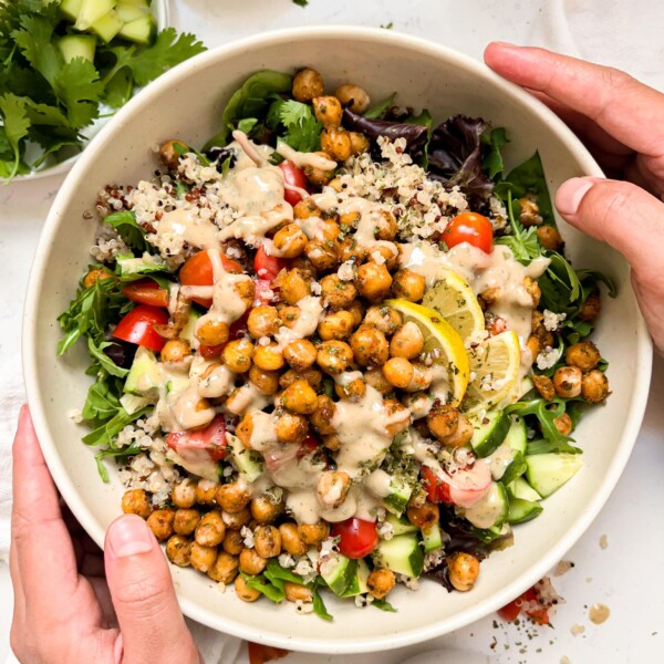 bowl with chickpeas, quinoa, greens and veggies next to a white linen napkin