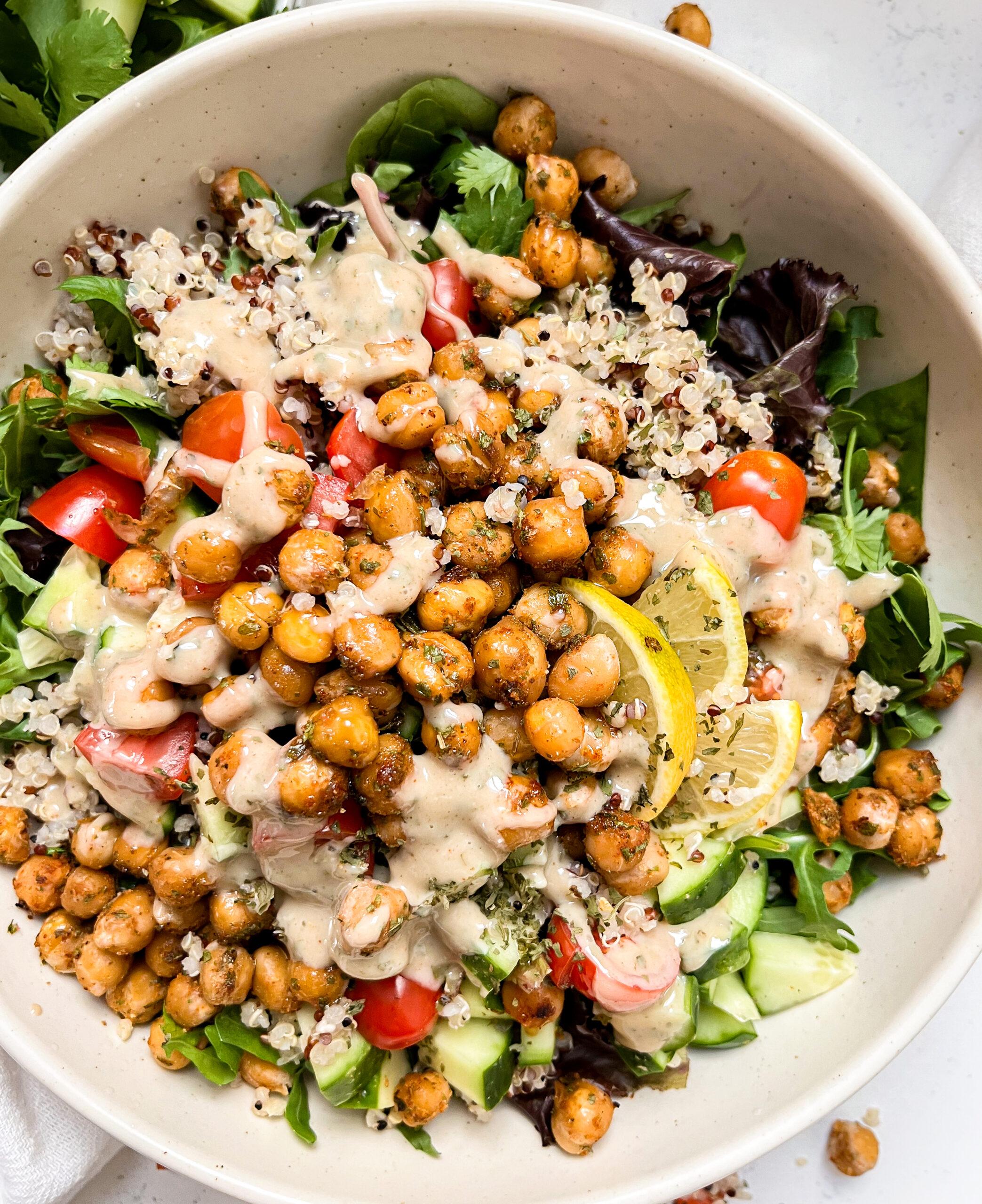 bowl with chickpeas, quinoa, greens and veggies next to a white linen napkin