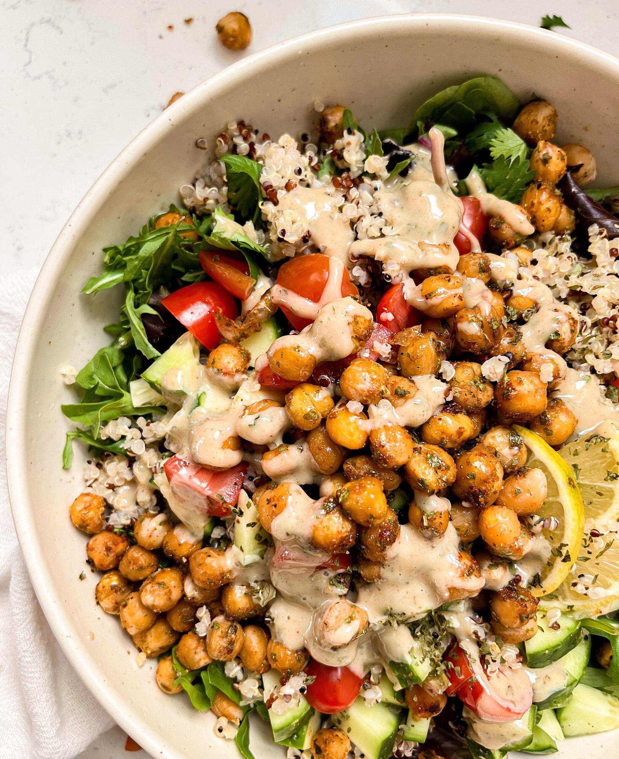 bowl with chickpeas, quinoa, greens and veggies next to a white linen napkin