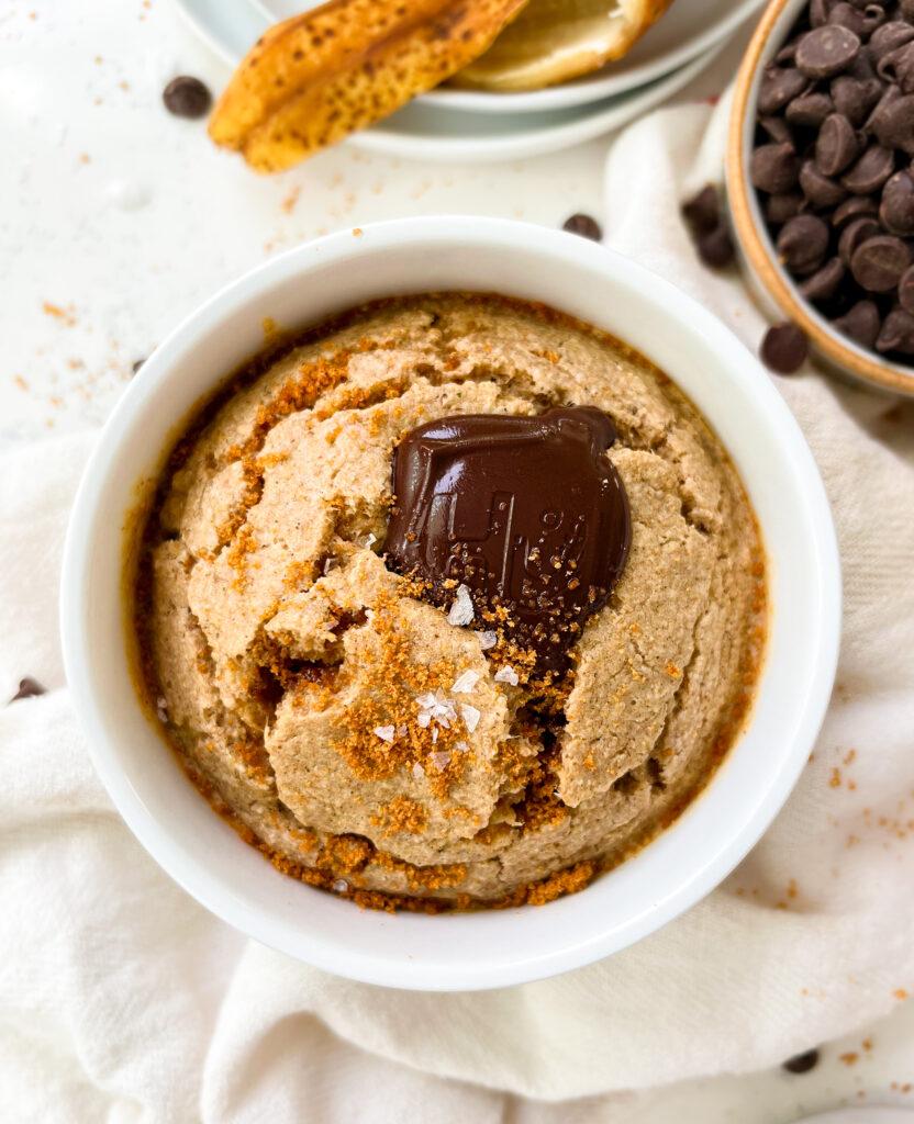 vegan banana bread baked oats in a white ramekin next to a banana peel and chocolate chips
