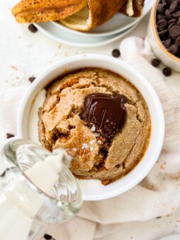 vegan banana bread baked oats in a white ramekin next to a banana peel and chocolate chips
