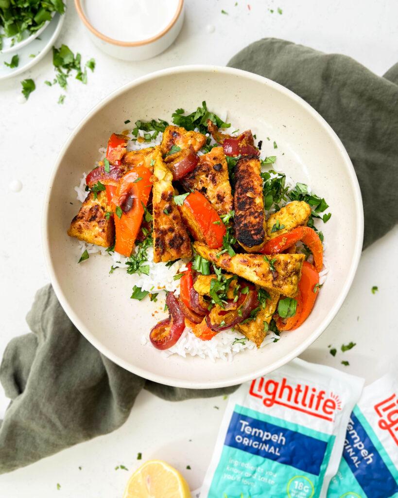 vegan shawarma bowl with middle eastern tofu, veggies and yogurt sauce on top