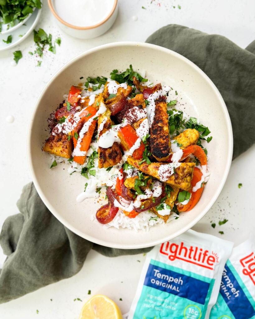 vegan shawarma bowl with middle eastern tofu, veggies and yogurt sauce on top