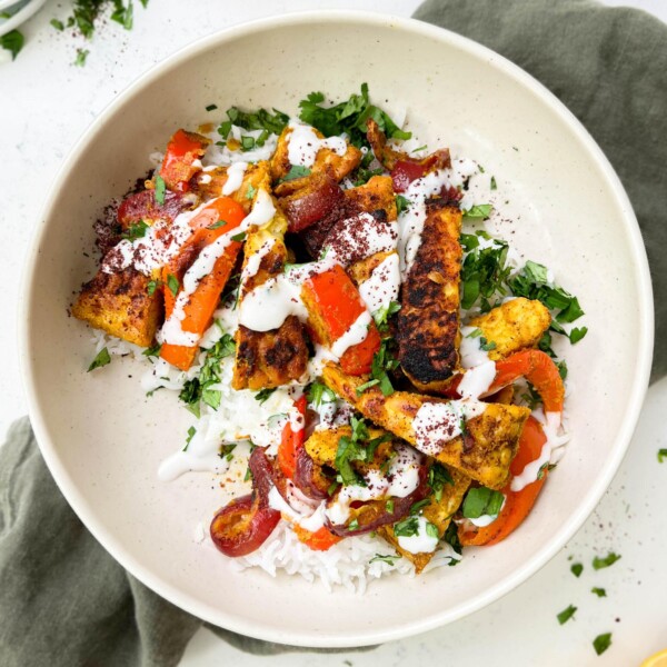 vegan shawarma bowl with middle eastern tofu, veggies and yogurt sauce on top