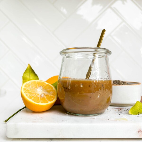 creamy balsamic vinaigrette dressing in a jar on a cutting board next to lemons