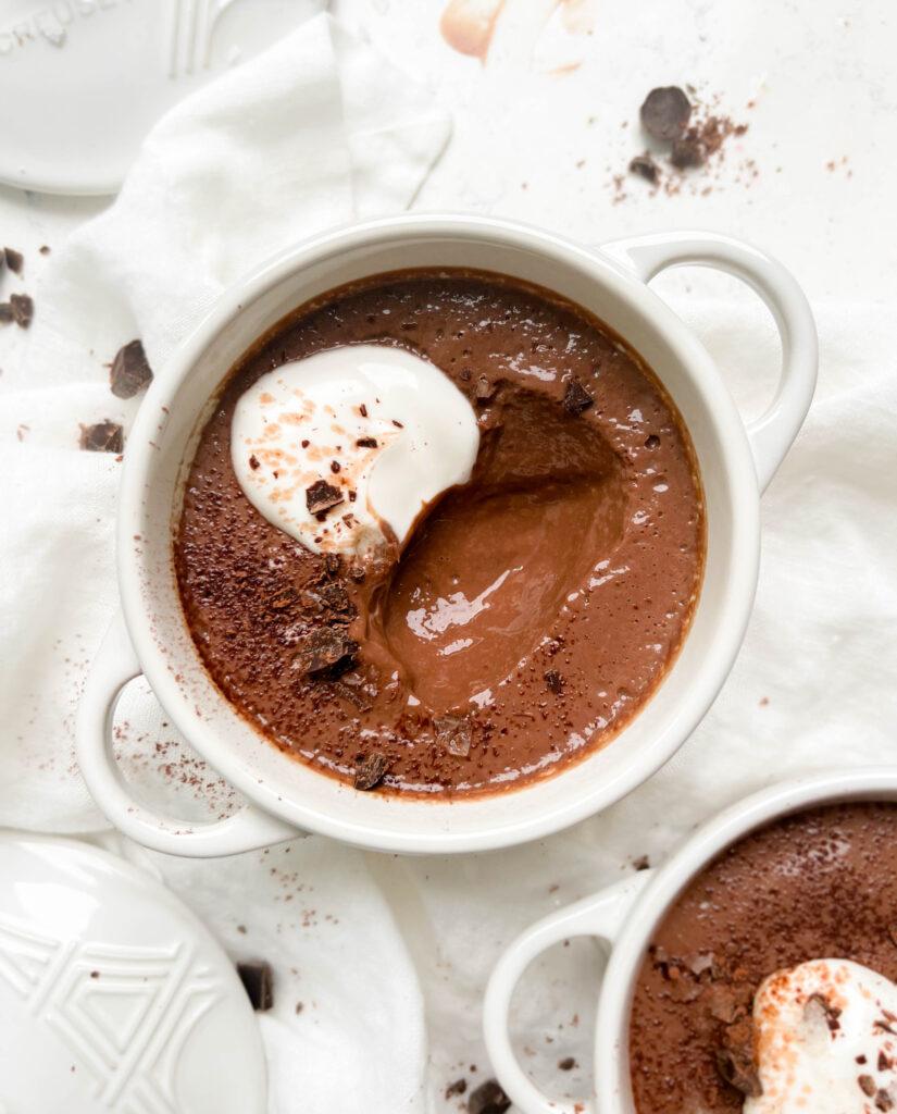 vegan chocolate pudding in a white ramekin with coconut yogurt and chocolate on top