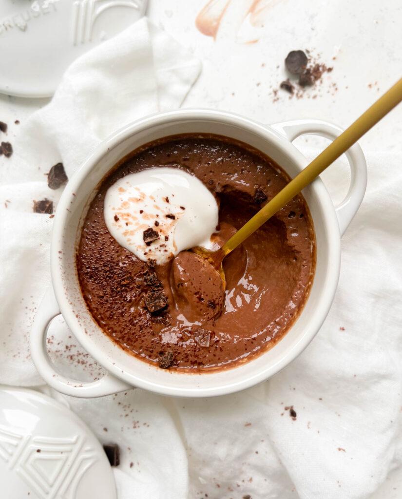 vegan chocolate pudding in a white ramekin with coconut yogurt and chocolate on top