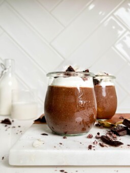 healthy chocolate seed pudding in a jar on a white cutting board next to chocolate and jar of milk