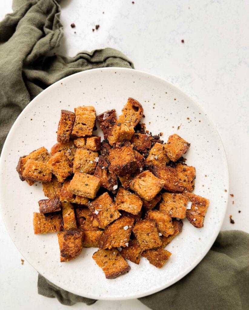 white speckled plate with homemade croutons on a green linen