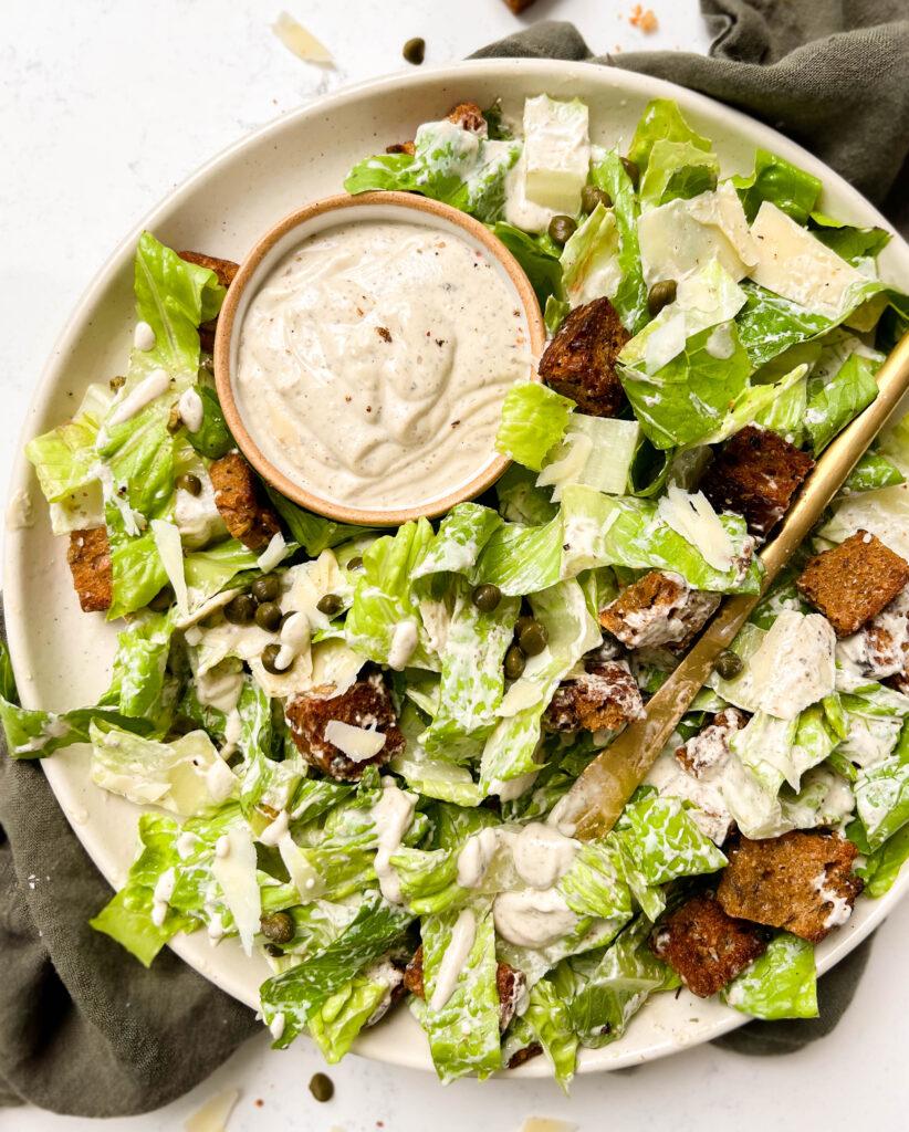a plate of vegan caesar salad on a green linen cloth