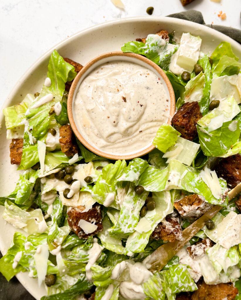 a plate of vegan caesar salad on a green linen cloth
