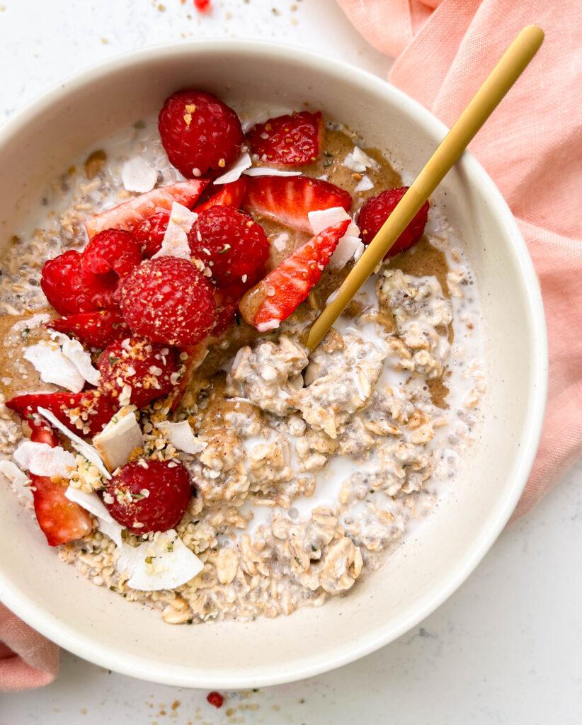 bowl of vanilla overnights oats with cashew milk, berries and coconut flakes on top