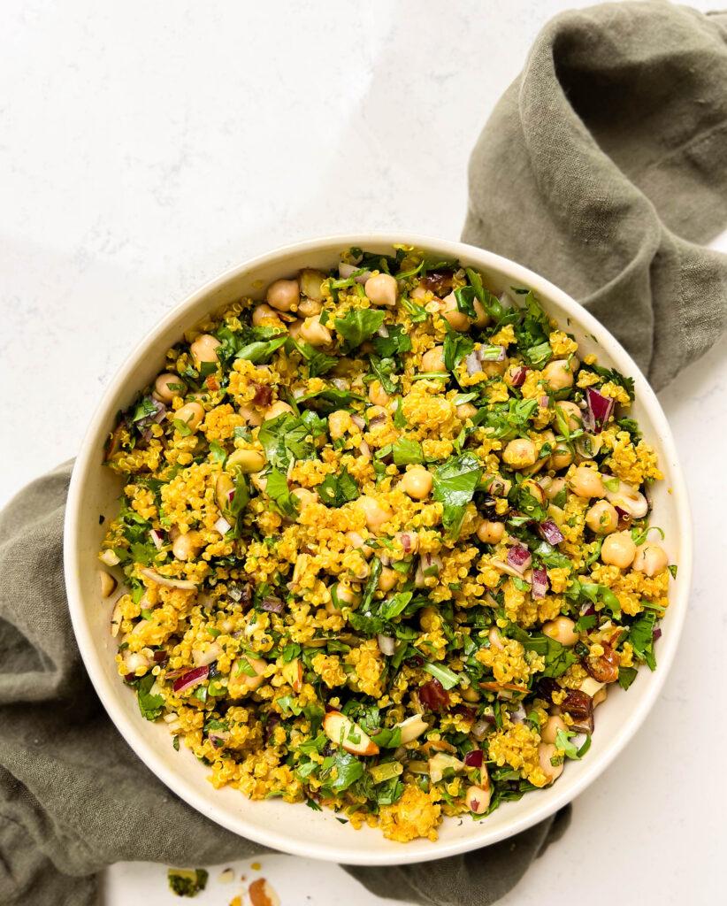 bowl of golden moroccan quinoa salad on a green linen cloth