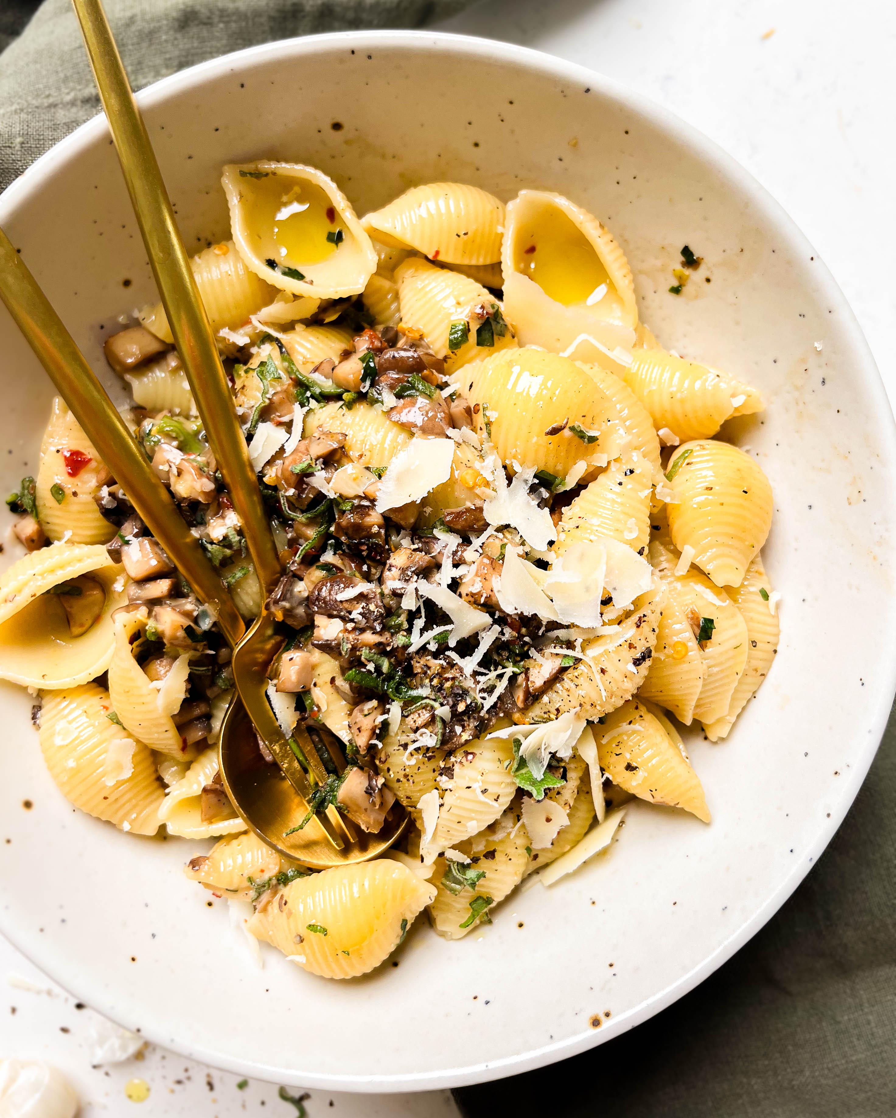 pasta in a beige bowl on a green linen cloth