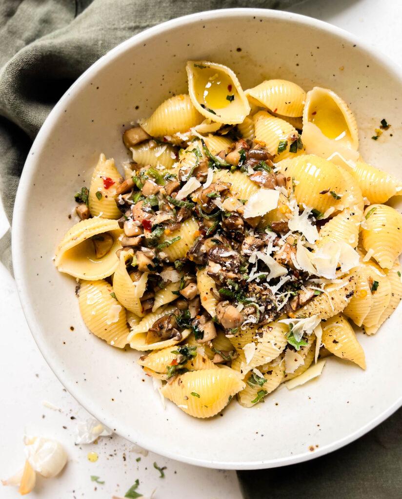 pasta in a beige bowl on a green linen cloth