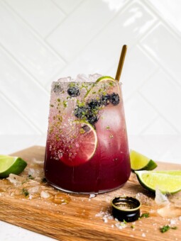 summer berry smash mocktail on cutting board with lime wedges