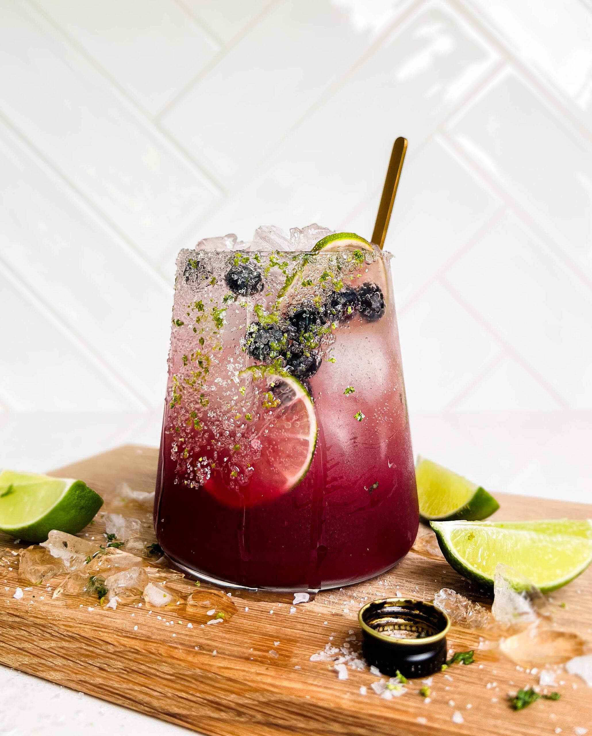 summer berry smash mocktail on cutting board with lime wedges