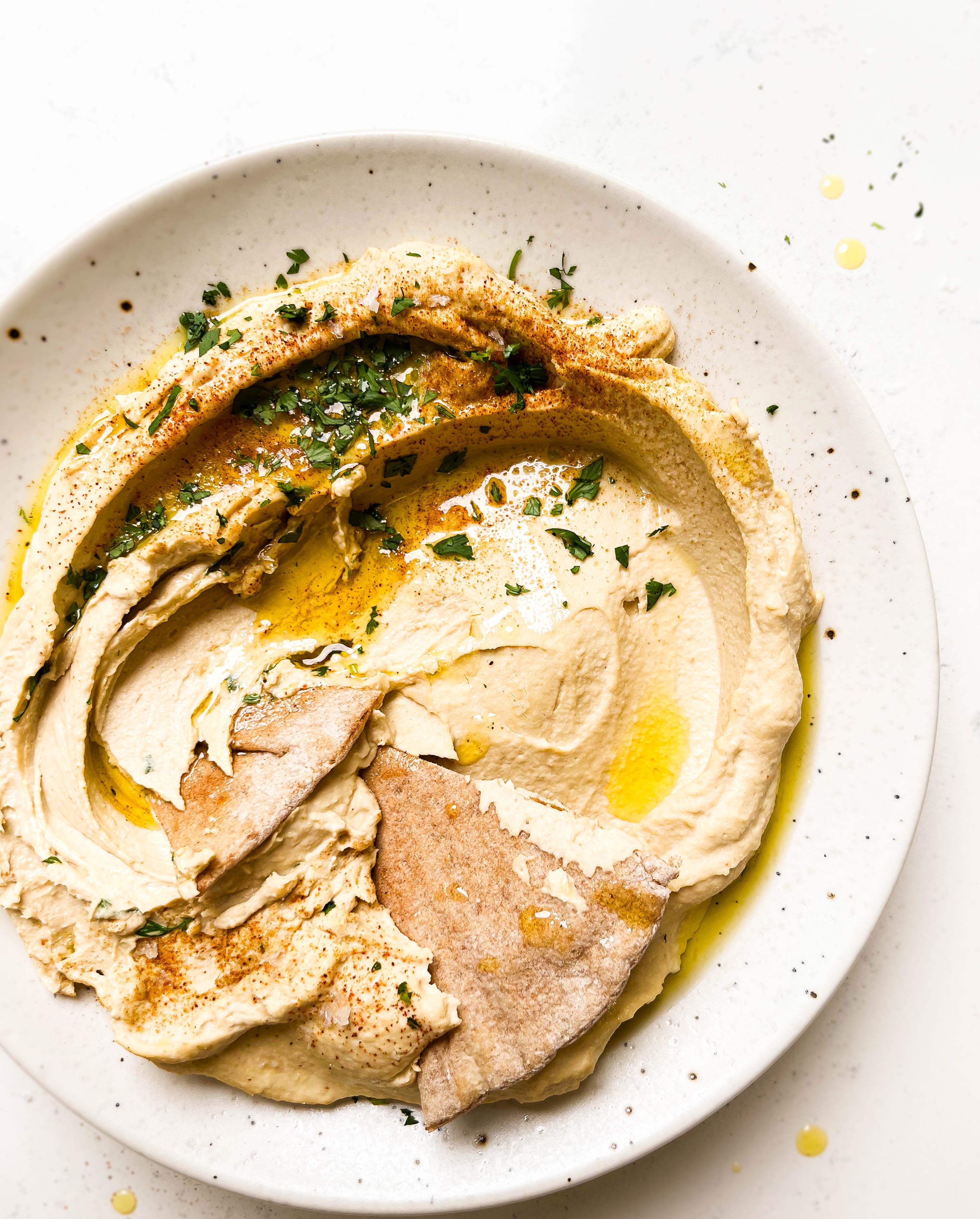homemade hummus on a speckled plate with pita bread