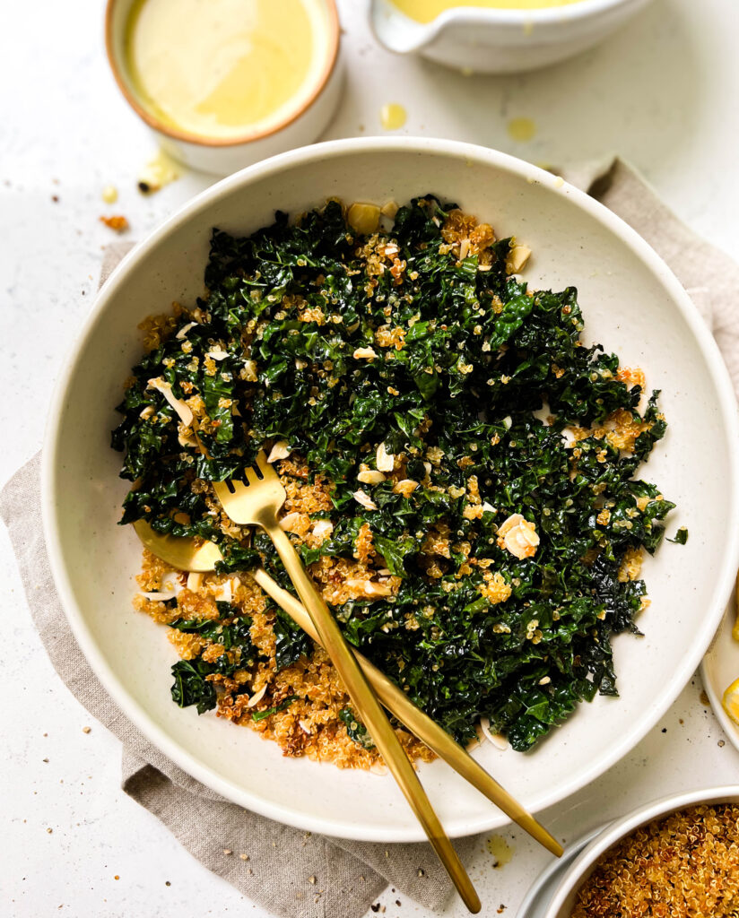 bowl of baked kale salad next to a bowl of lemon vinaigrette