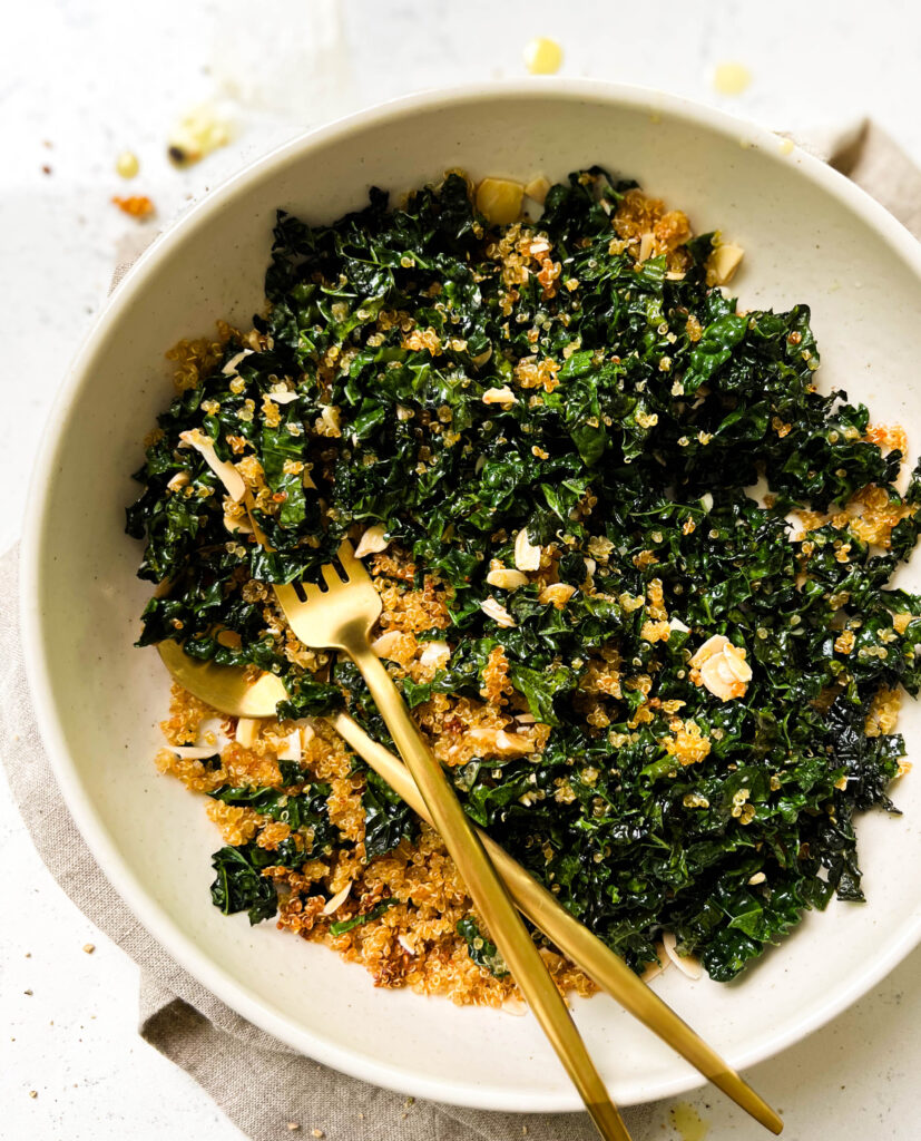bowl of baked kale salad next to a bowl of lemon vinaigrette