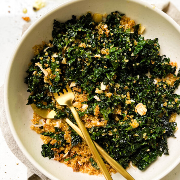 bowl of baked kale salad next to a bowl of lemon vinaigrette