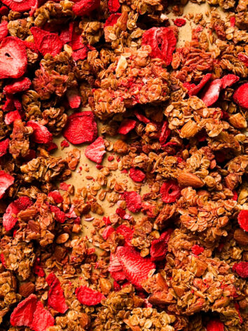 strawberry almond granola on a gold sheet pan
