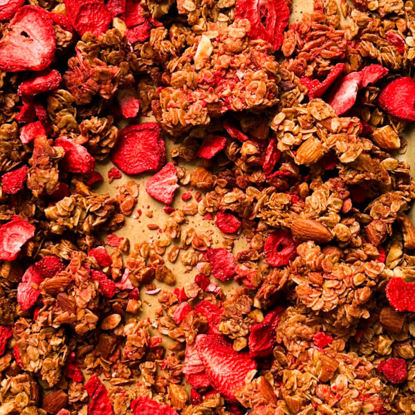 strawberry almond granola on a gold sheet pan