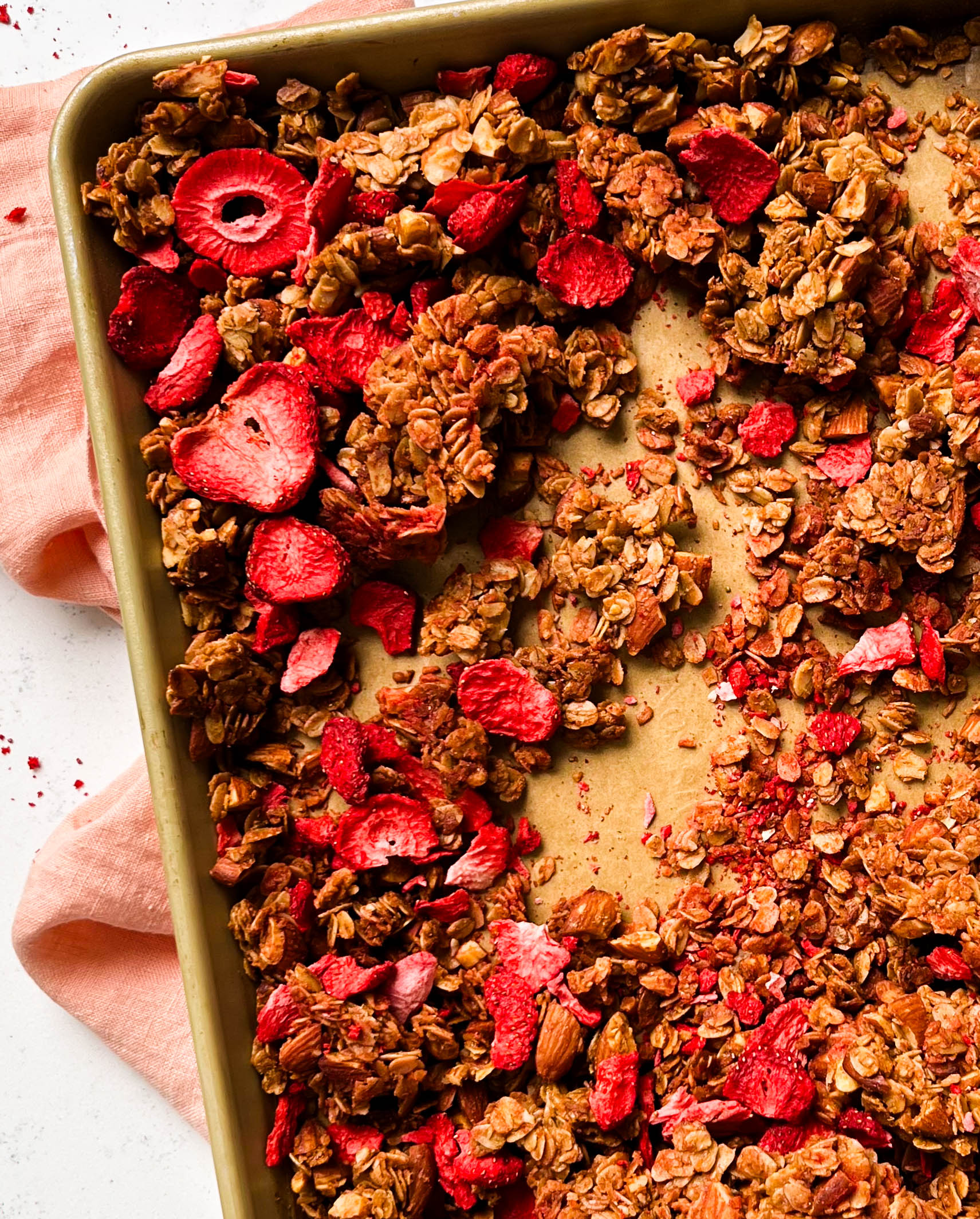 strawberry almond granola on a gold sheet pan
