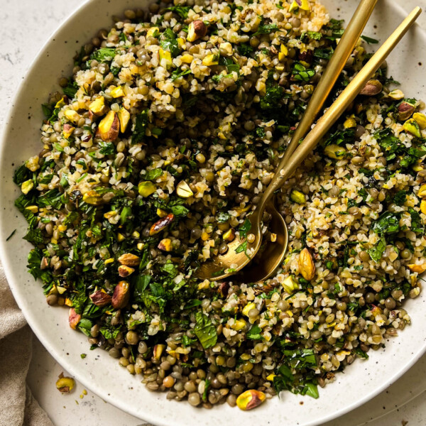 bulgur salad in a bowl with two gold spoons