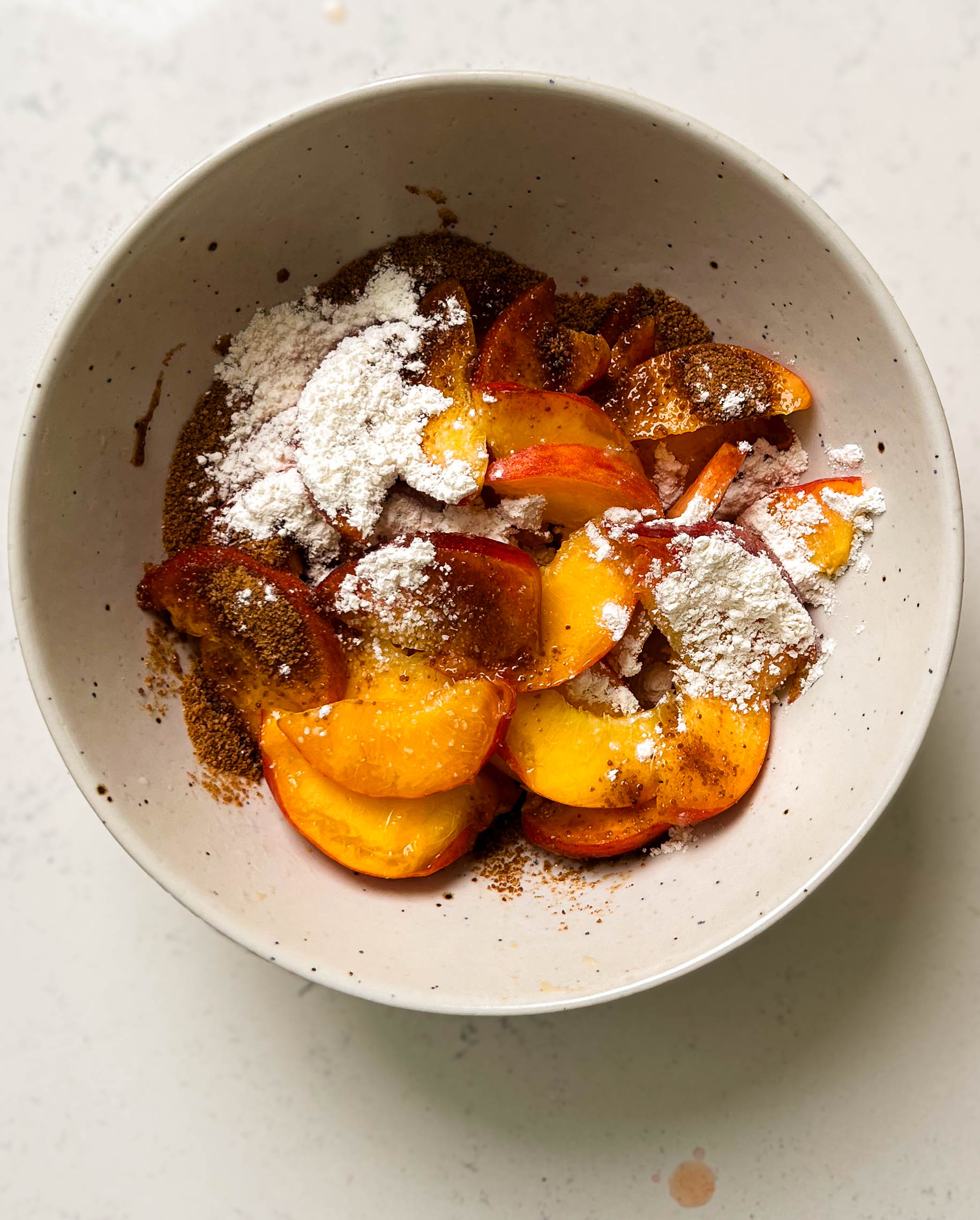 sliced peaches in a bowl with coconut sugar on top
