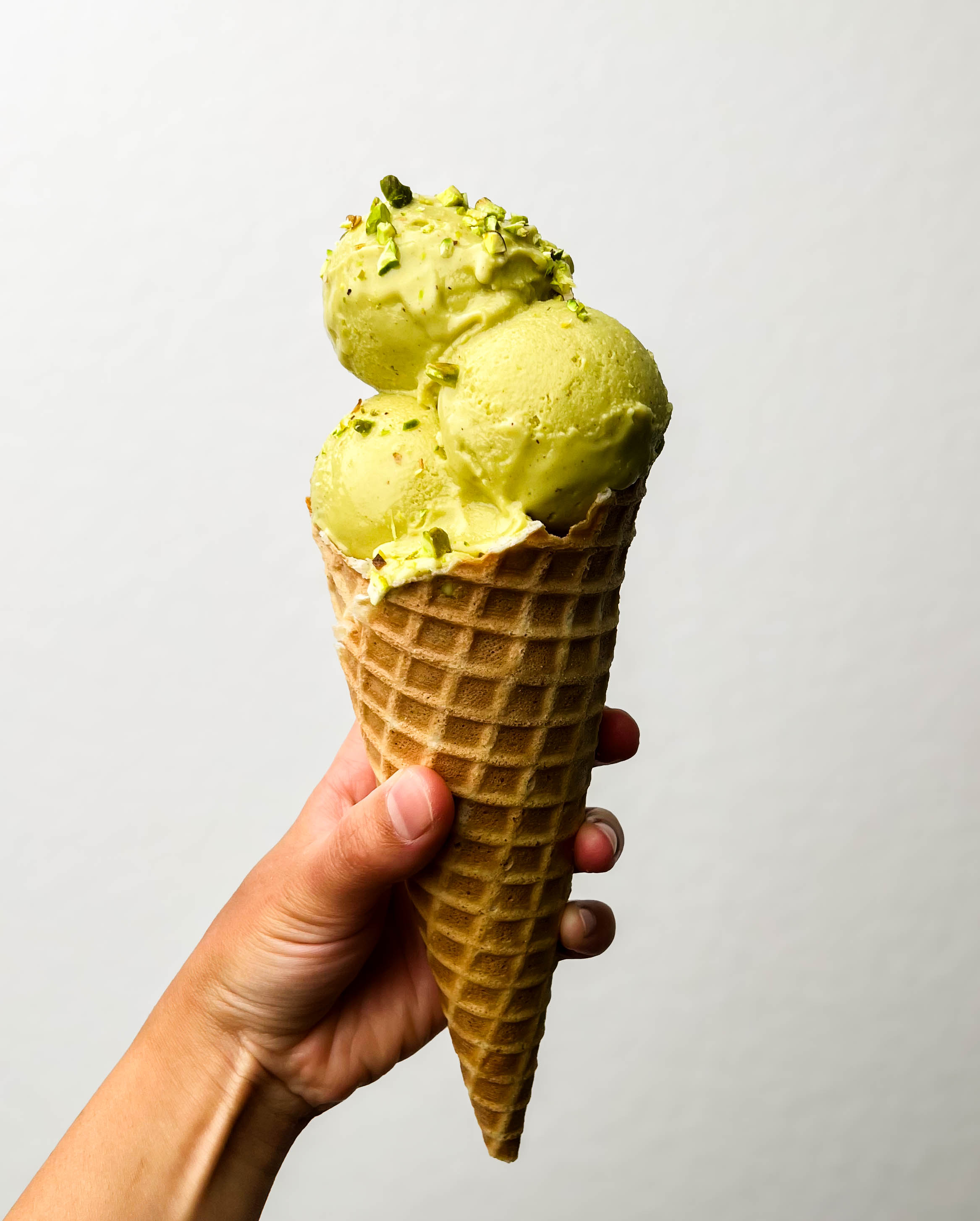 homemade cardamom pistachio ice cream in a cone
